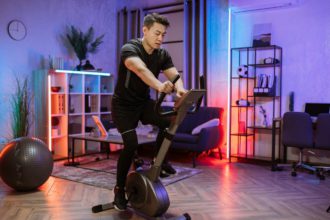 Home fitness workout, young asian man athlete training on smart stationary bike indoors