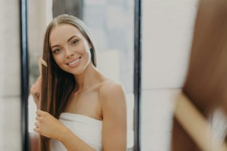 Portrait of beautiful gorgeous woman with bare shoulders combes her straight hair