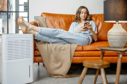 Woman sitting near air purifier and moisturizer appliance